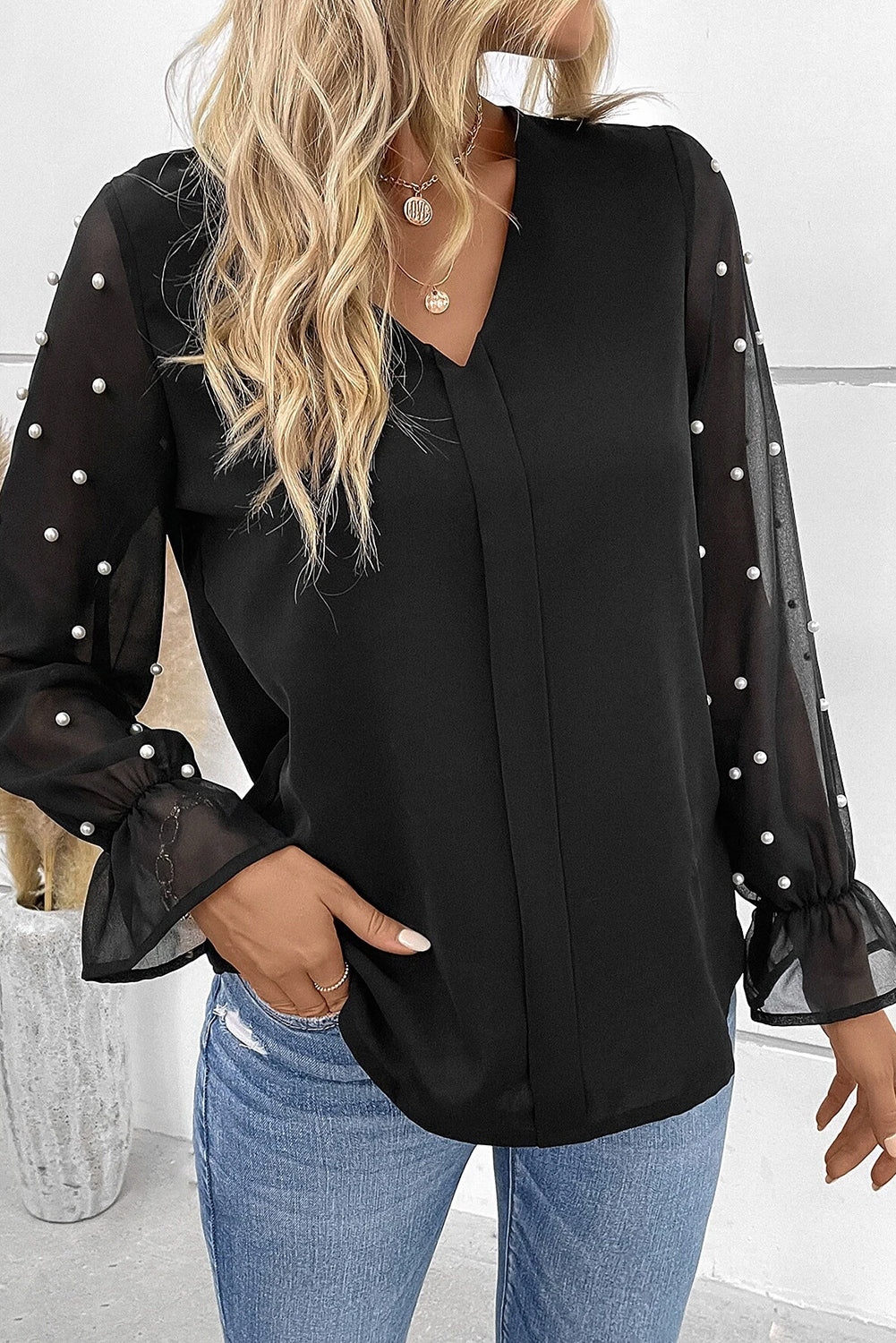 Blouse noire à col en V et manches en maille perlée